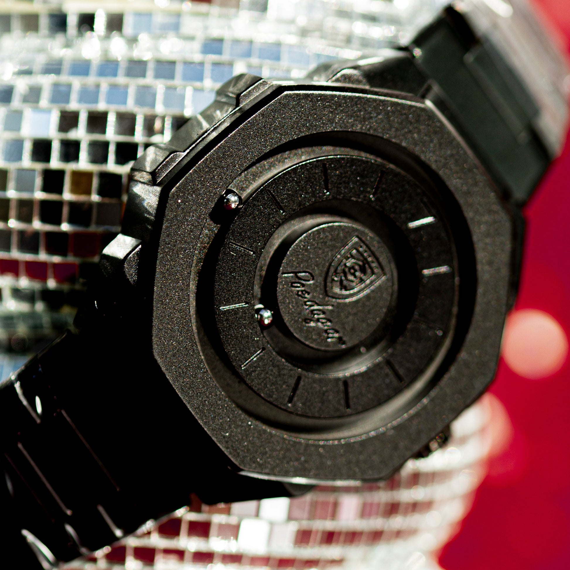 Black watch with a brand logo held against a disco ball background