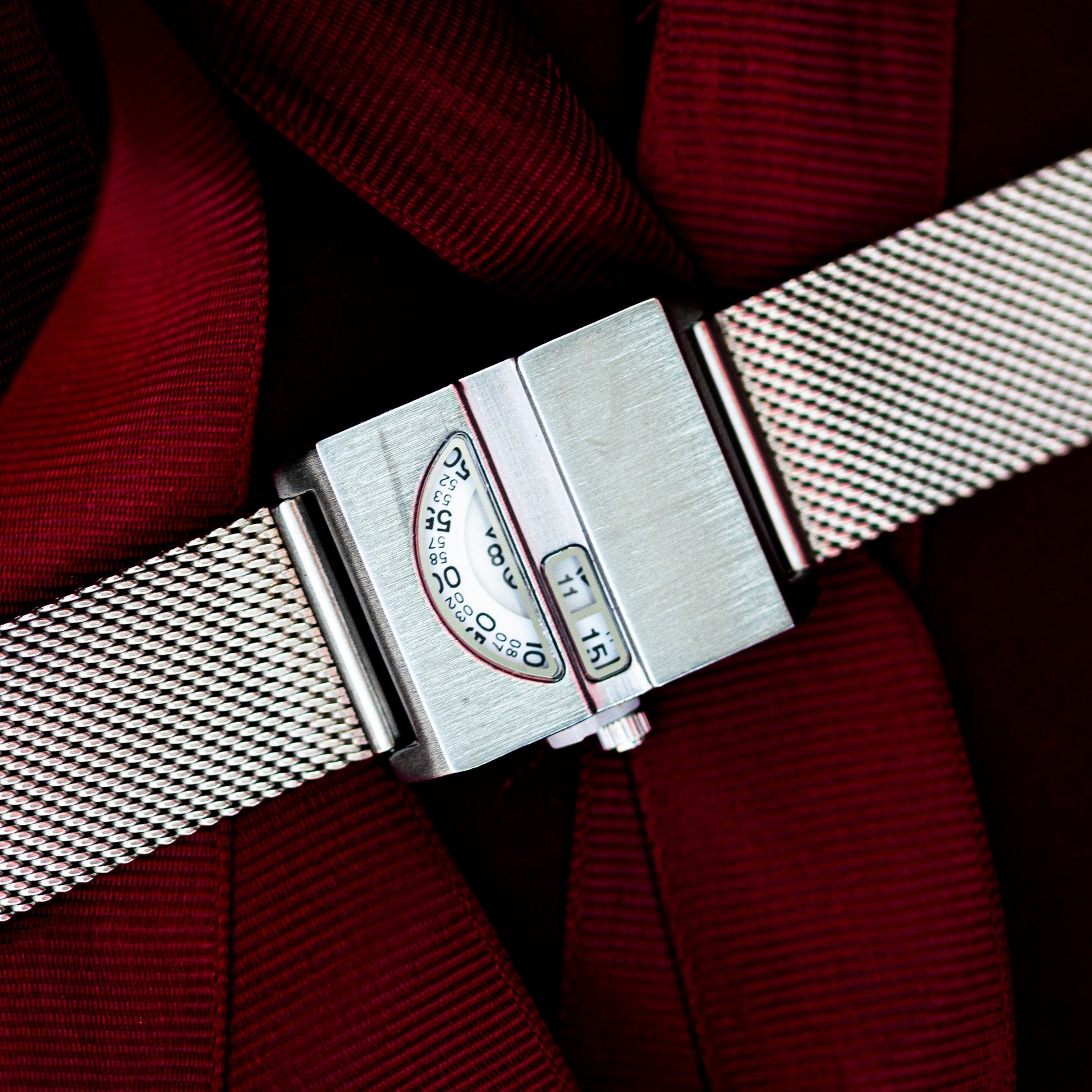 Close-up of a silver watch strap on a red fabric background