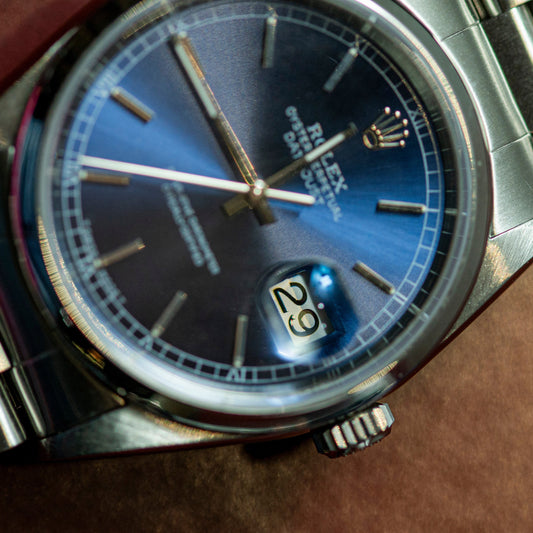 Close-up of a silver watch with a blue face on a brown surface