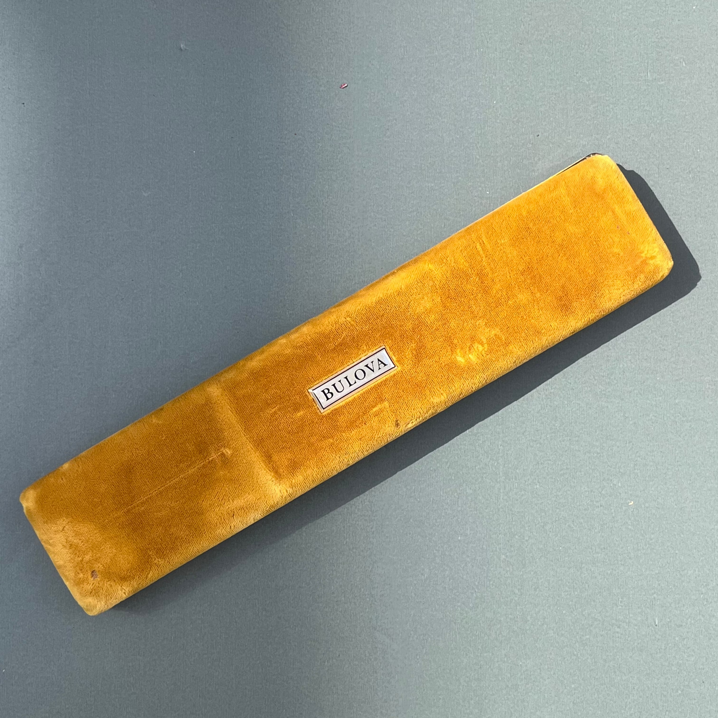 Brown rectangular object with 'Bulova' label on a gray background