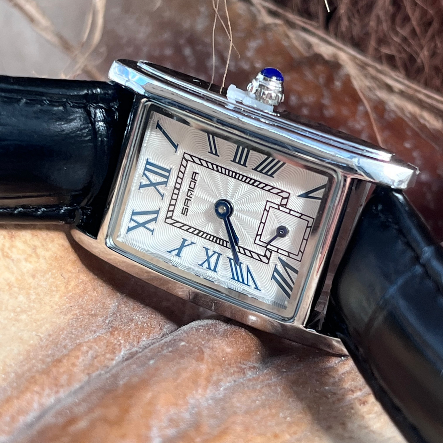 Silver watch with black strap on a textured surface