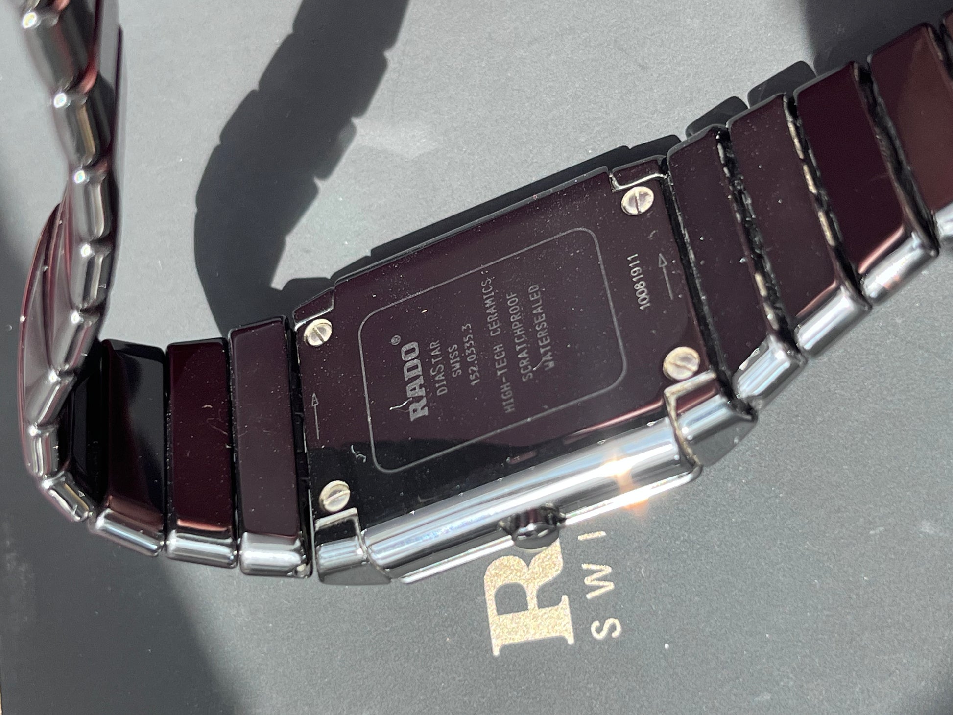 Close-up of a watch band with brand name on a gray surface