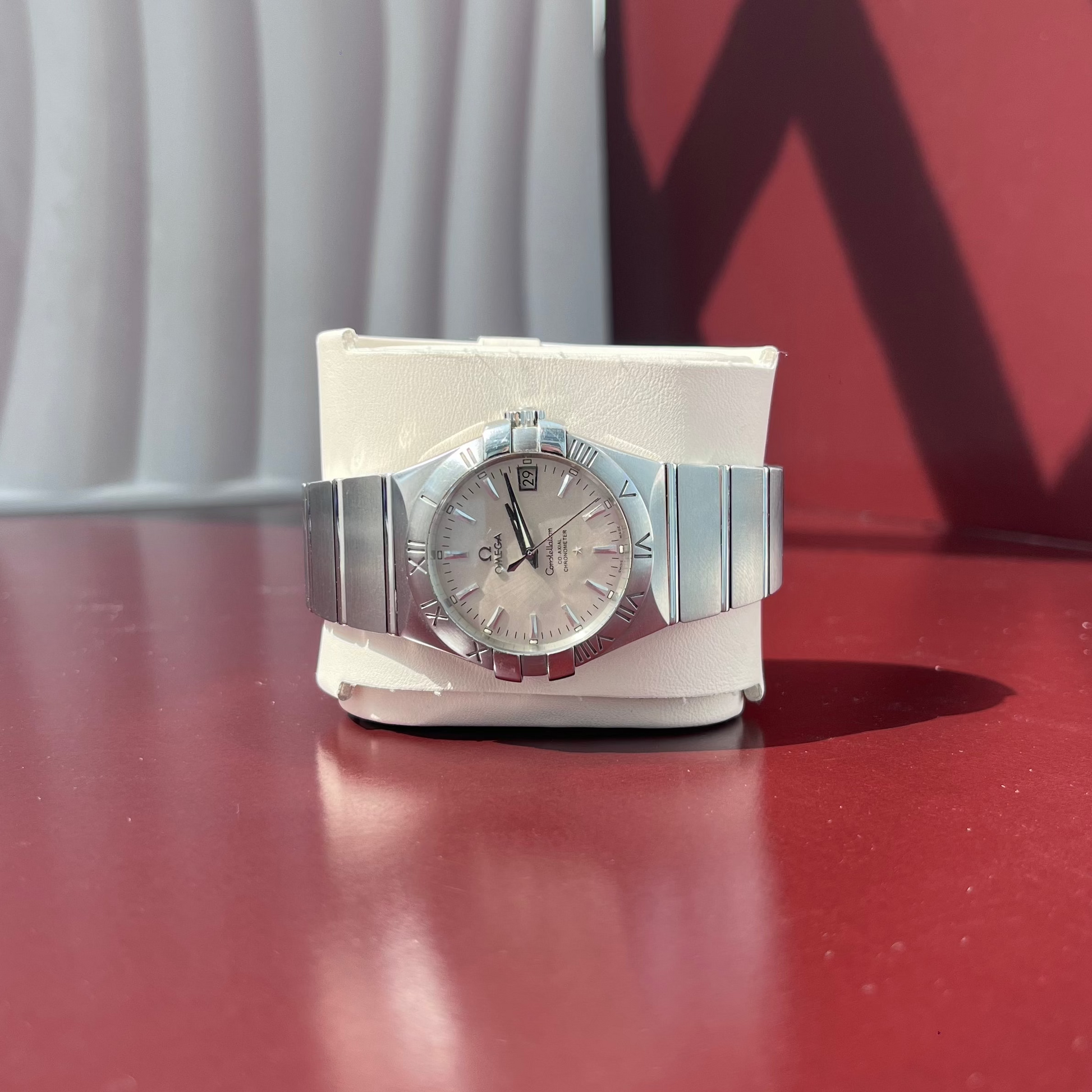 Silver watch on a stand with a red and white background