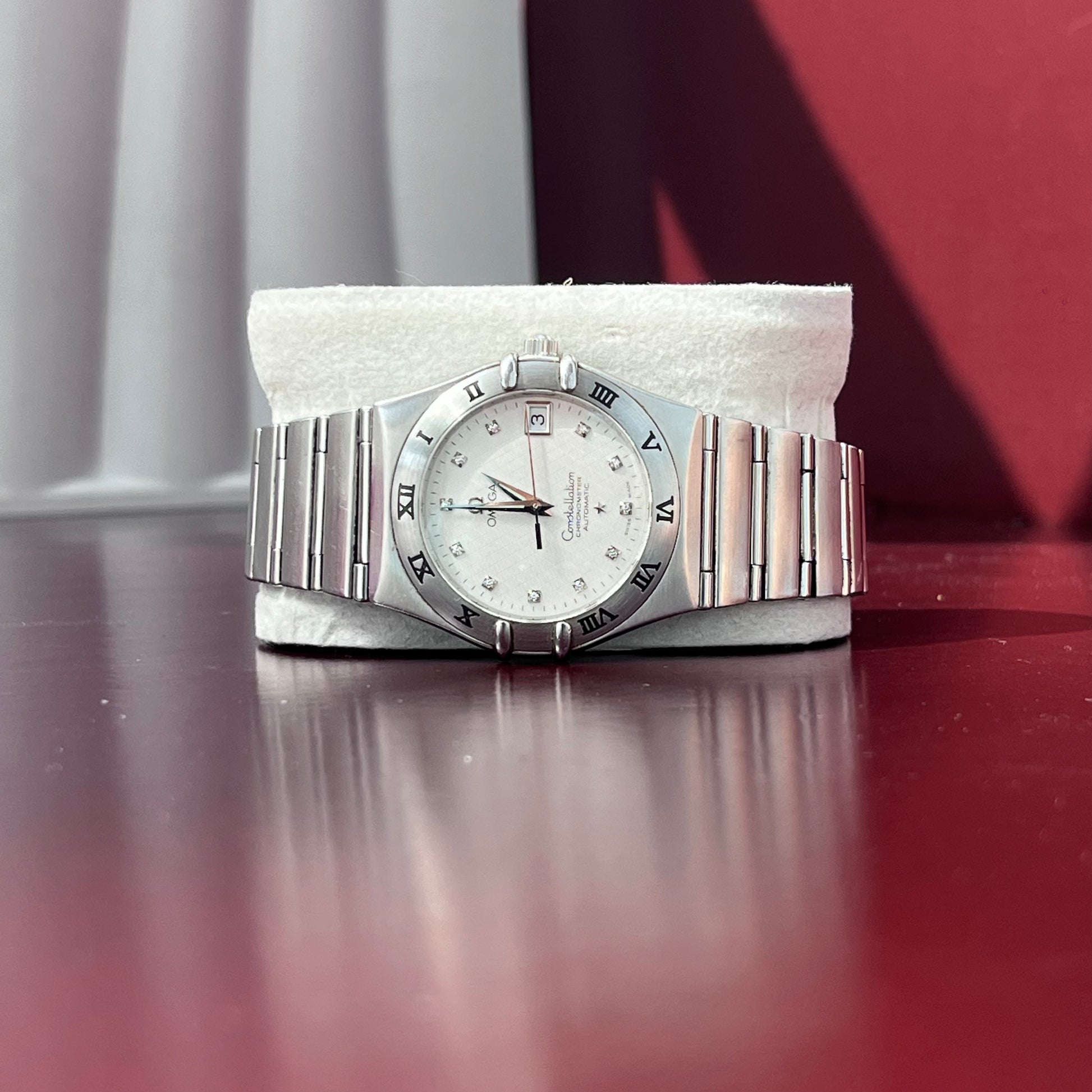 Silver wristwatch with a white face on a red surface
