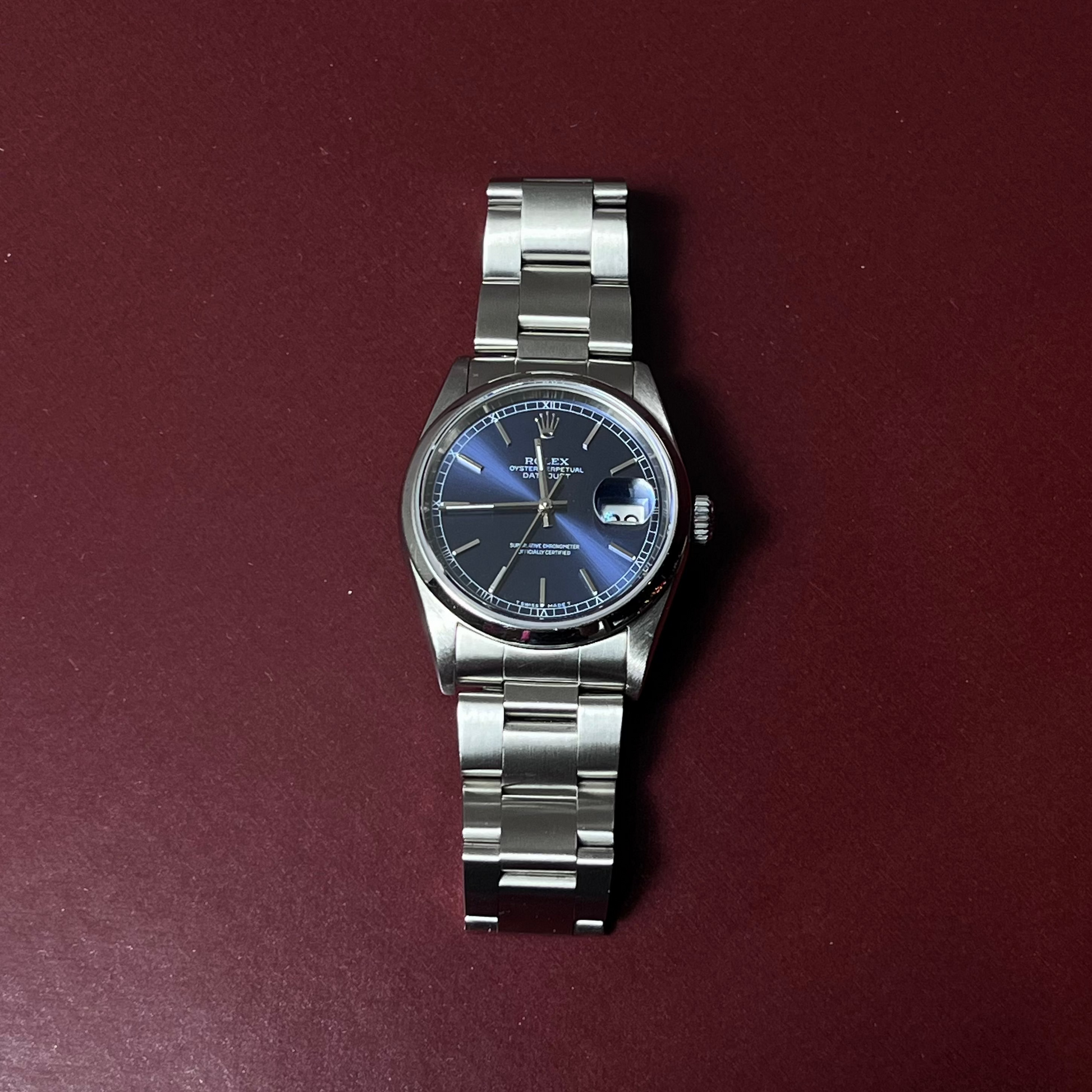 Silver watch with a blue face on a maroon background