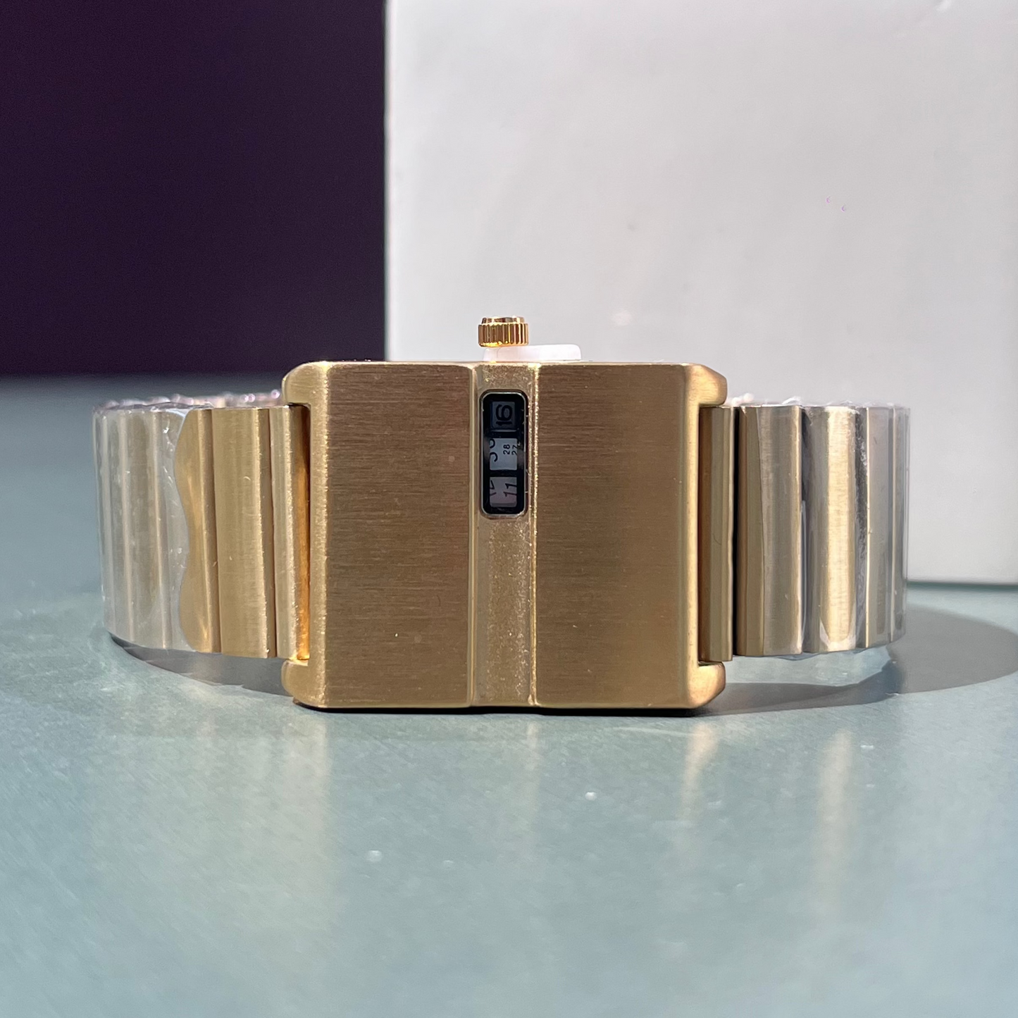 Gold bracelet on a reflective surface with a blurred background
