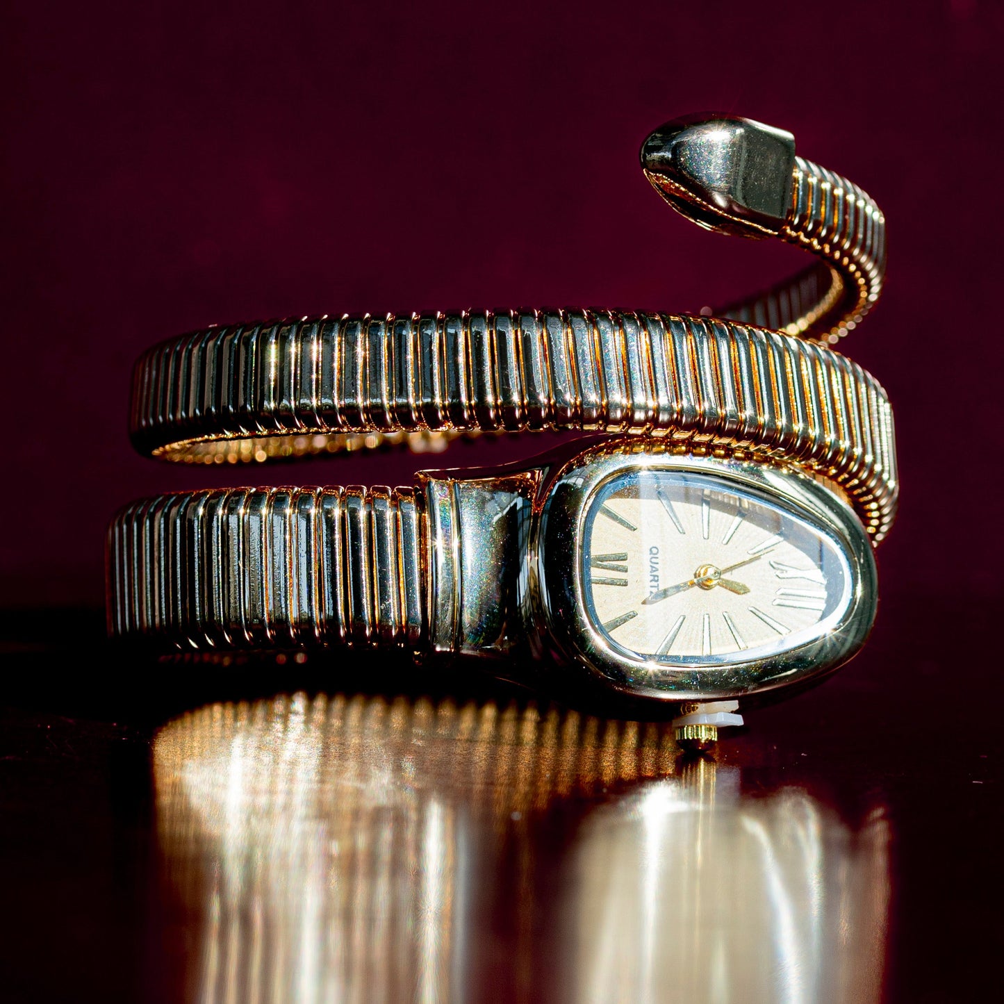 Silver snake-shaped watch on a reflective surface with a dark background