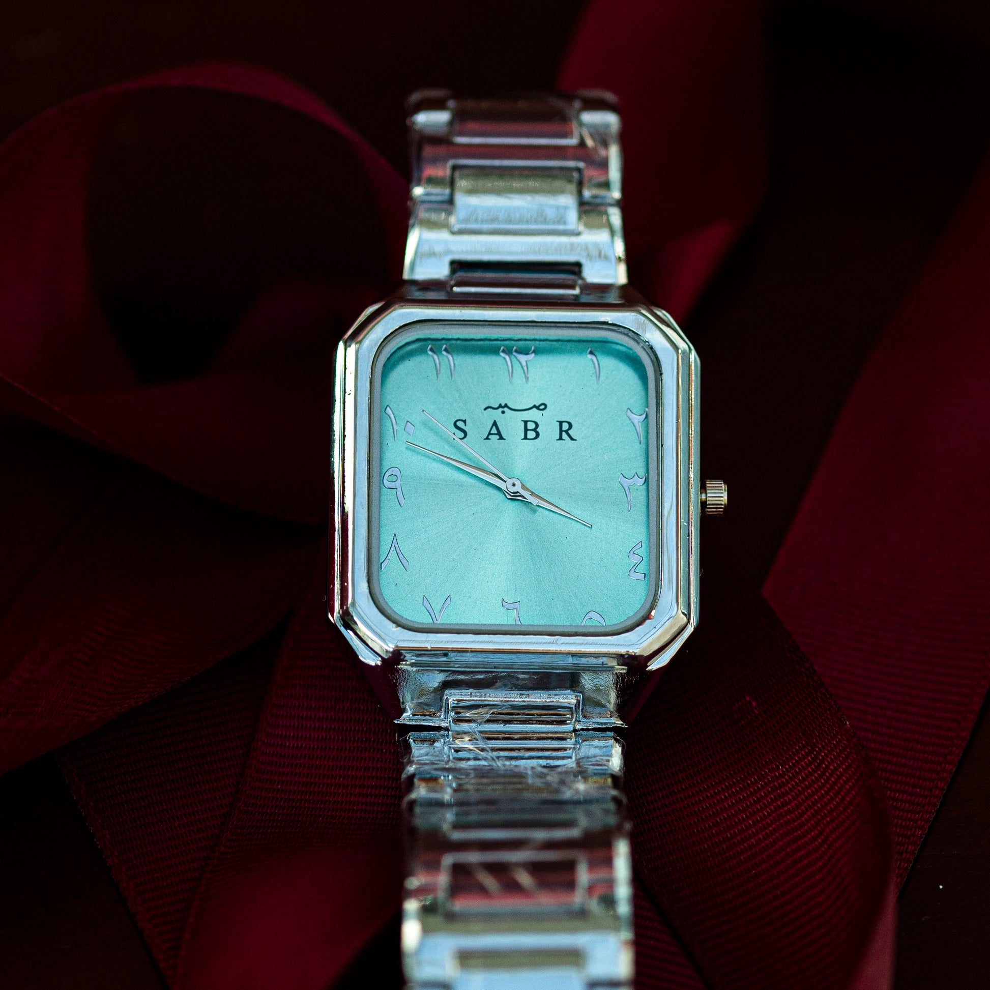 Silver watch with 'SABR' branding on a reflective surface