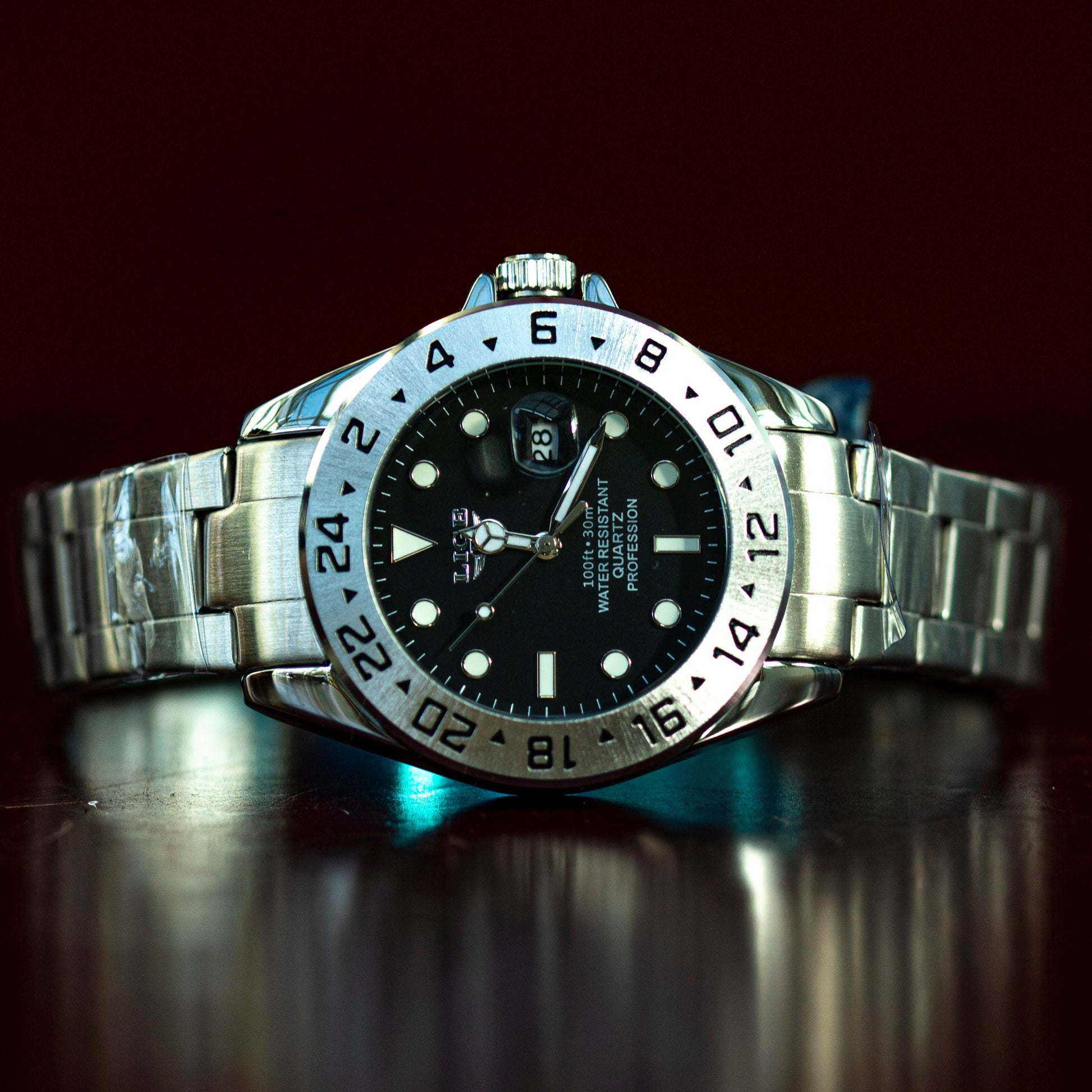 Silver watch with a black dial on a reflective surface