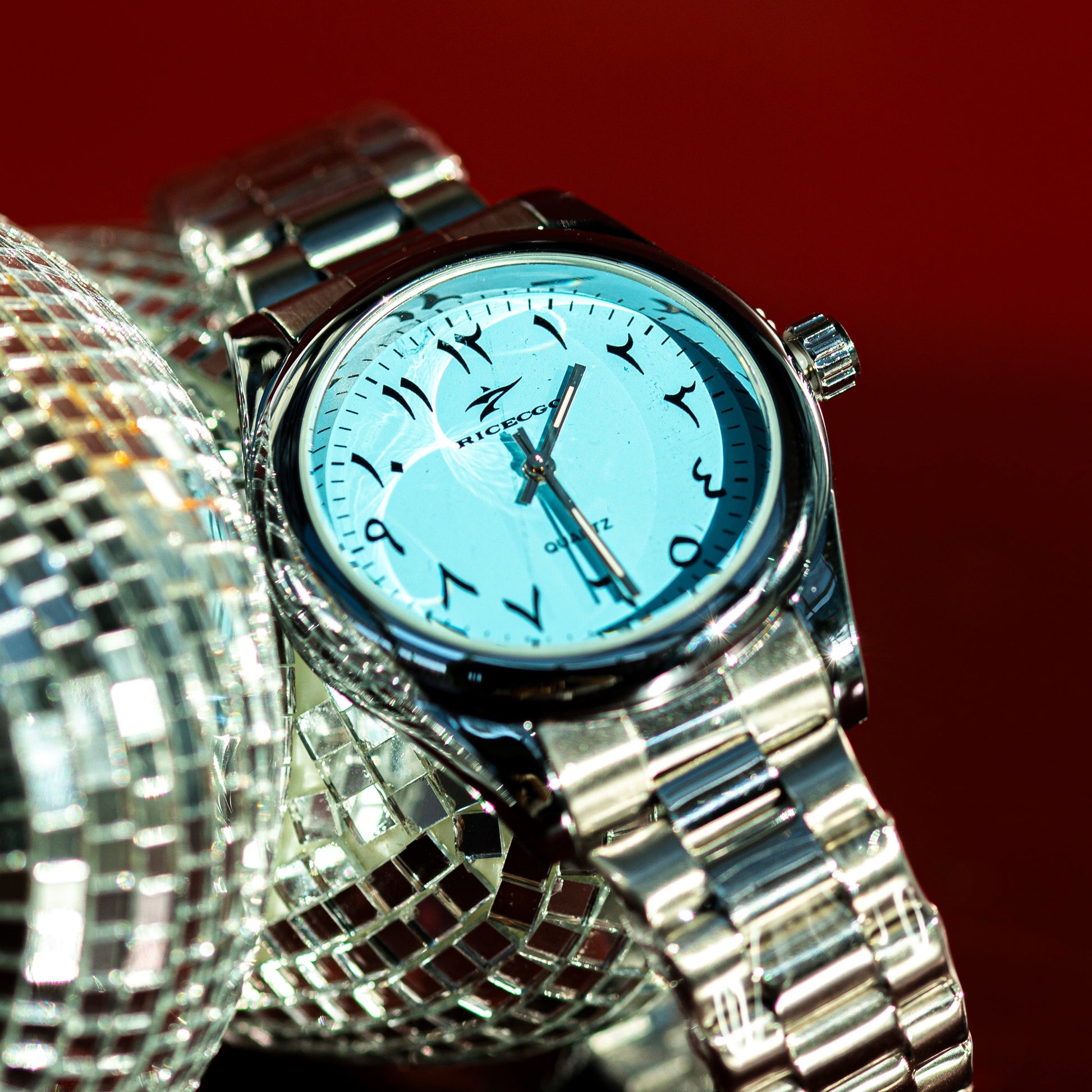 Silver watch with a blue face on a reflective surface