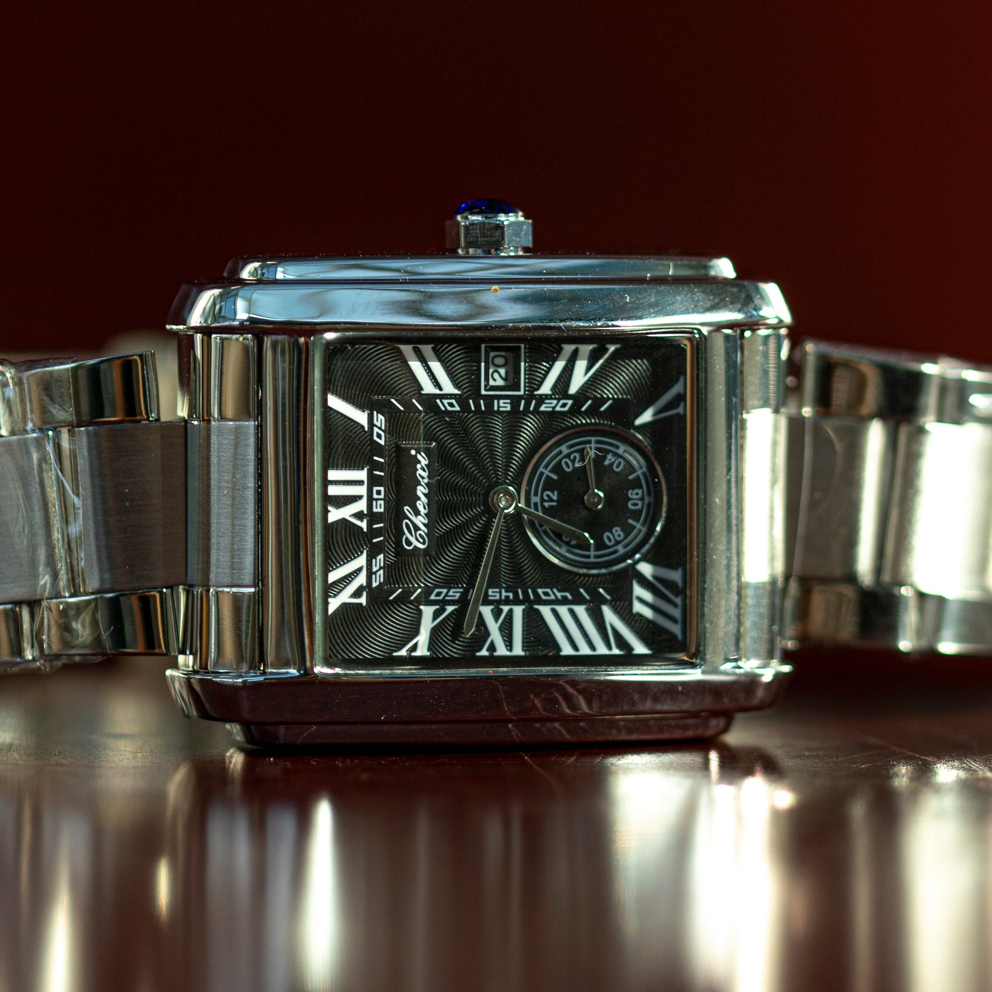 Silver wristwatch with a reflective surface on a dark background