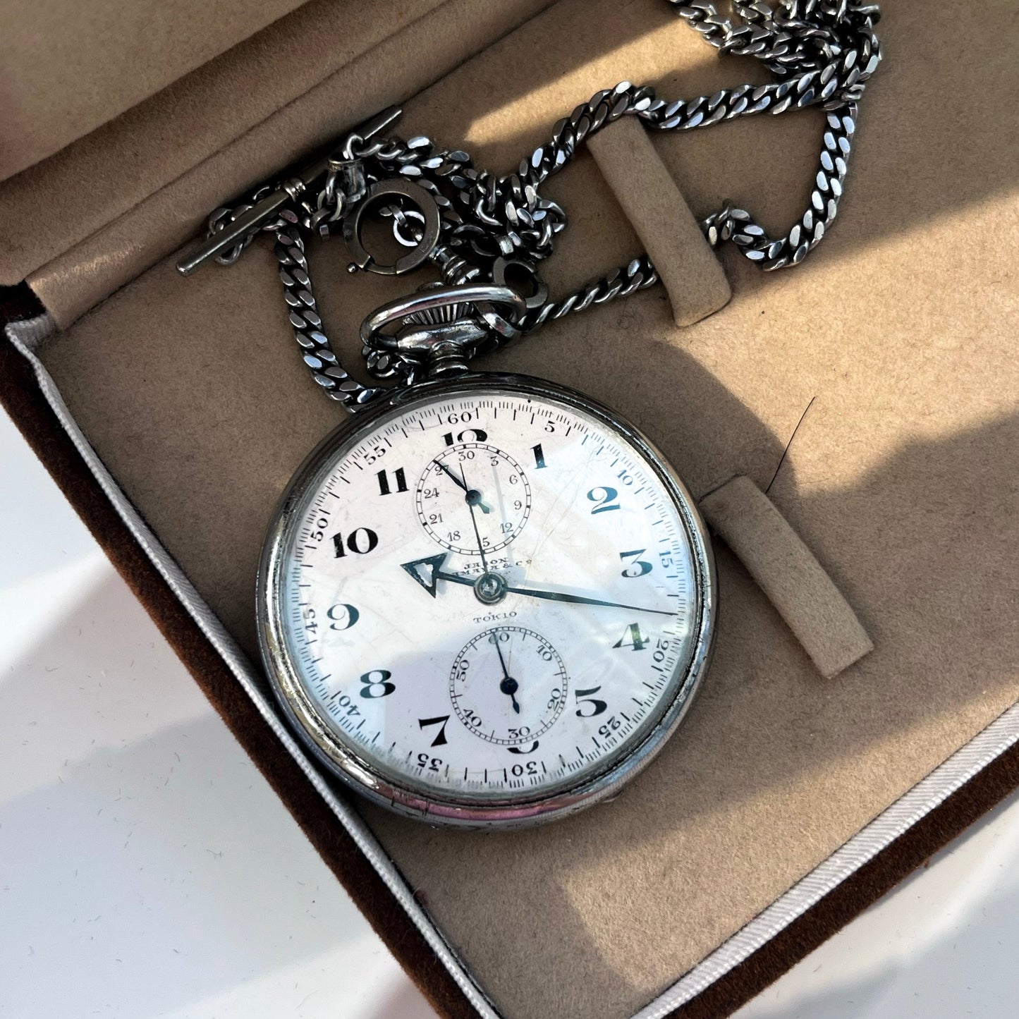 Vintage pocket watch with chain in an open box on a light background