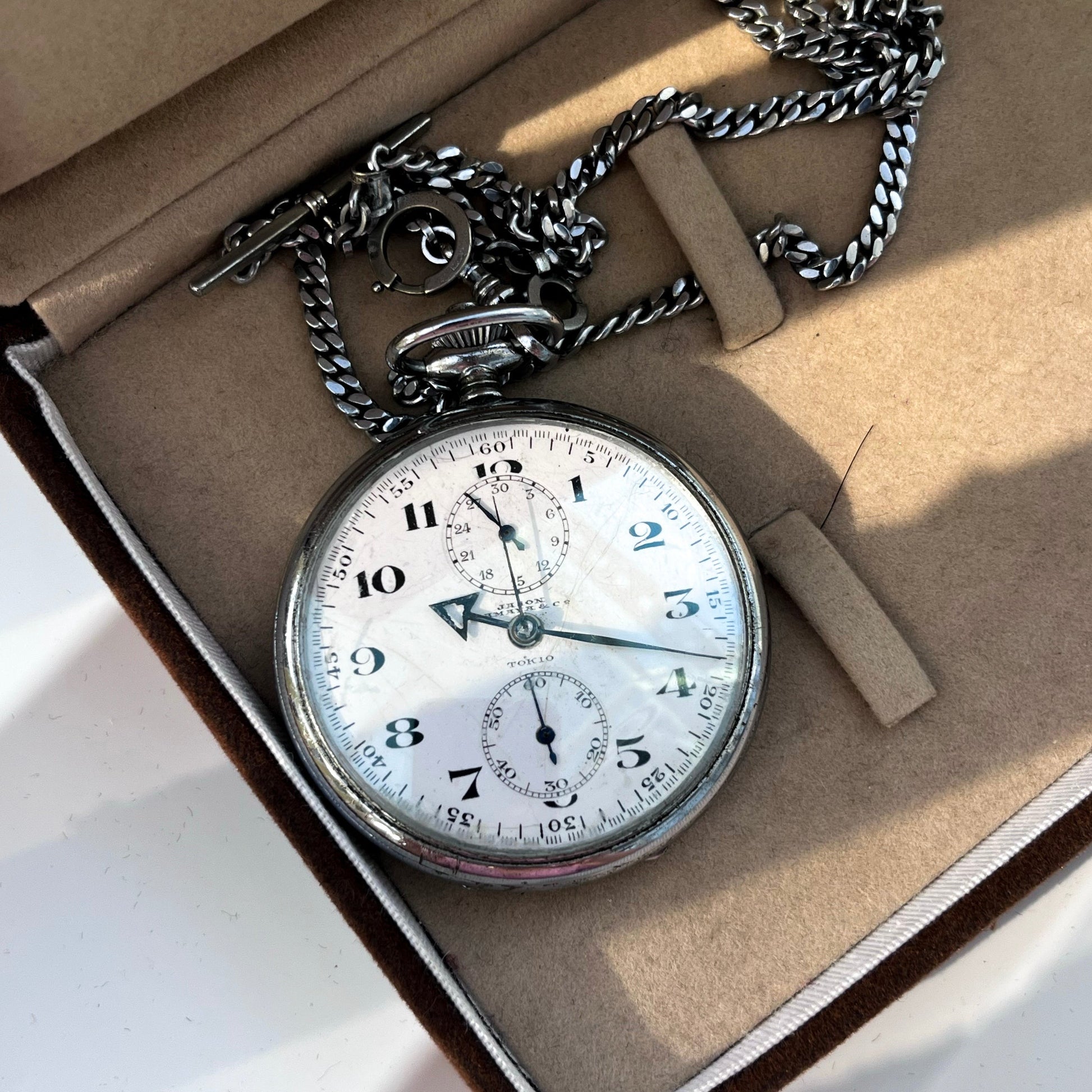 Vintage pocket watch with chain in an open box on a light background