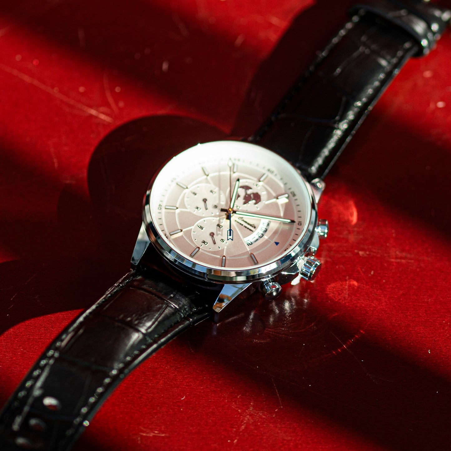 Watch with a black leather strap on a red surface
