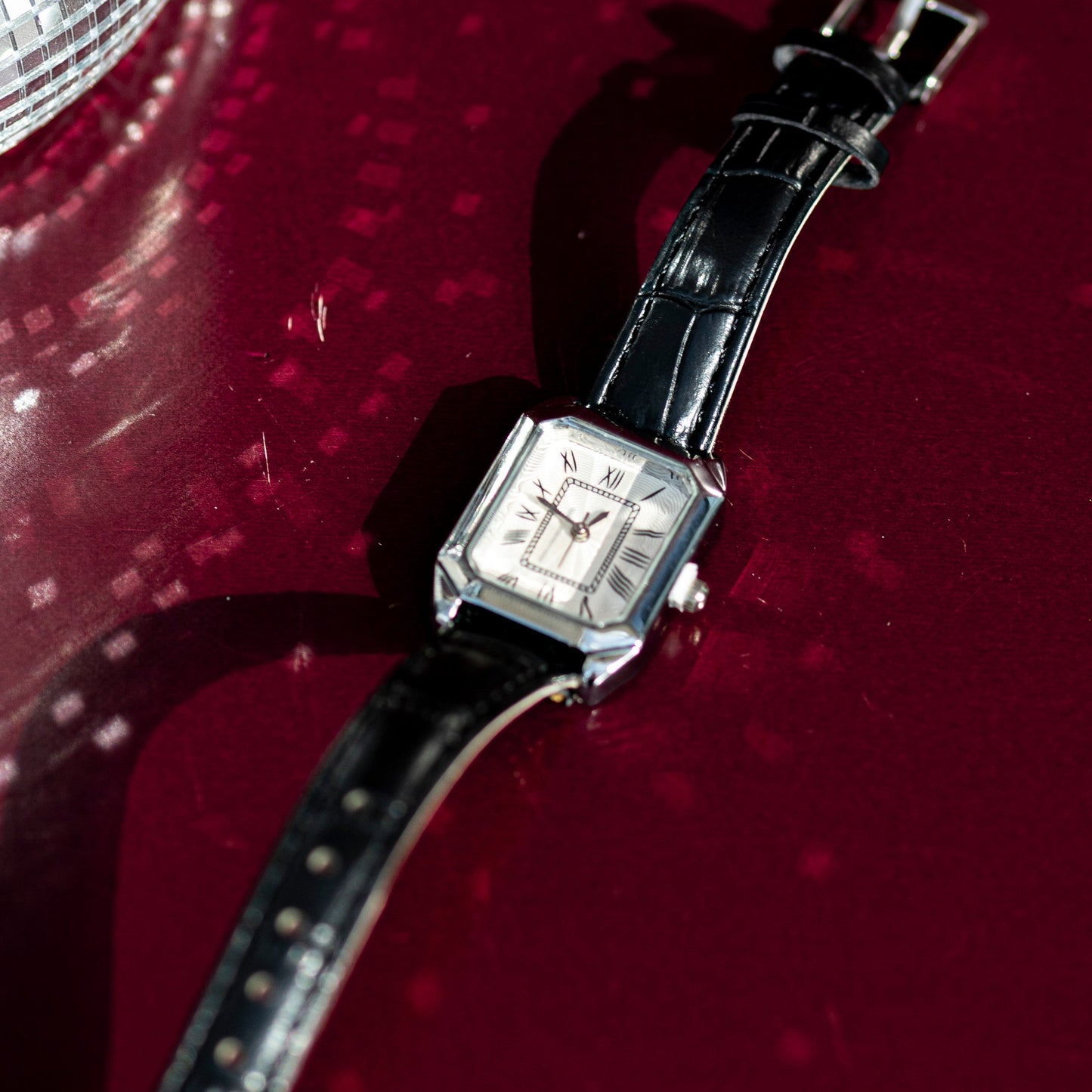Wristwatch with black strap on a red background