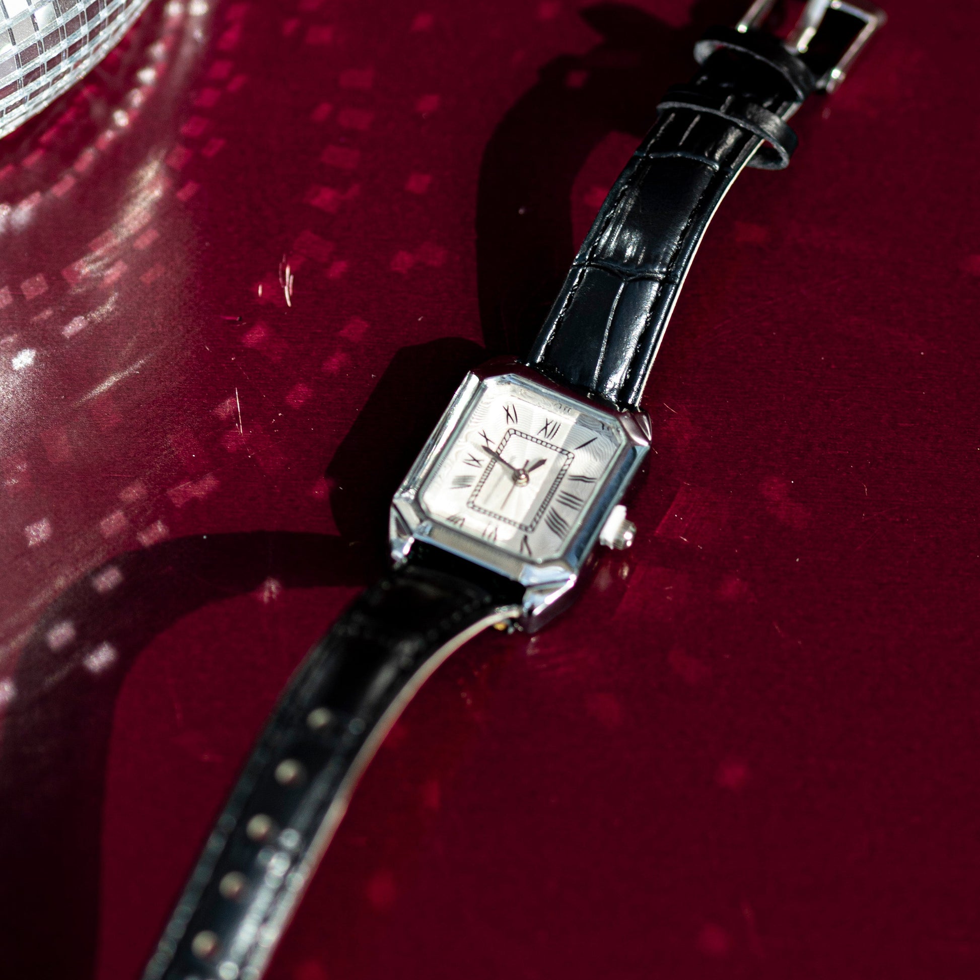 Wristwatch with black strap on a red background